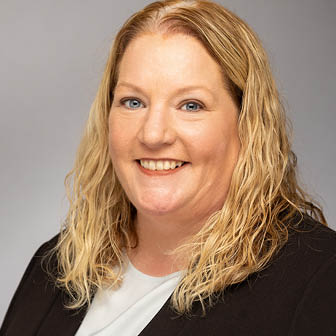 A woman wearing a black suit and white shirt. Description generated by AI
