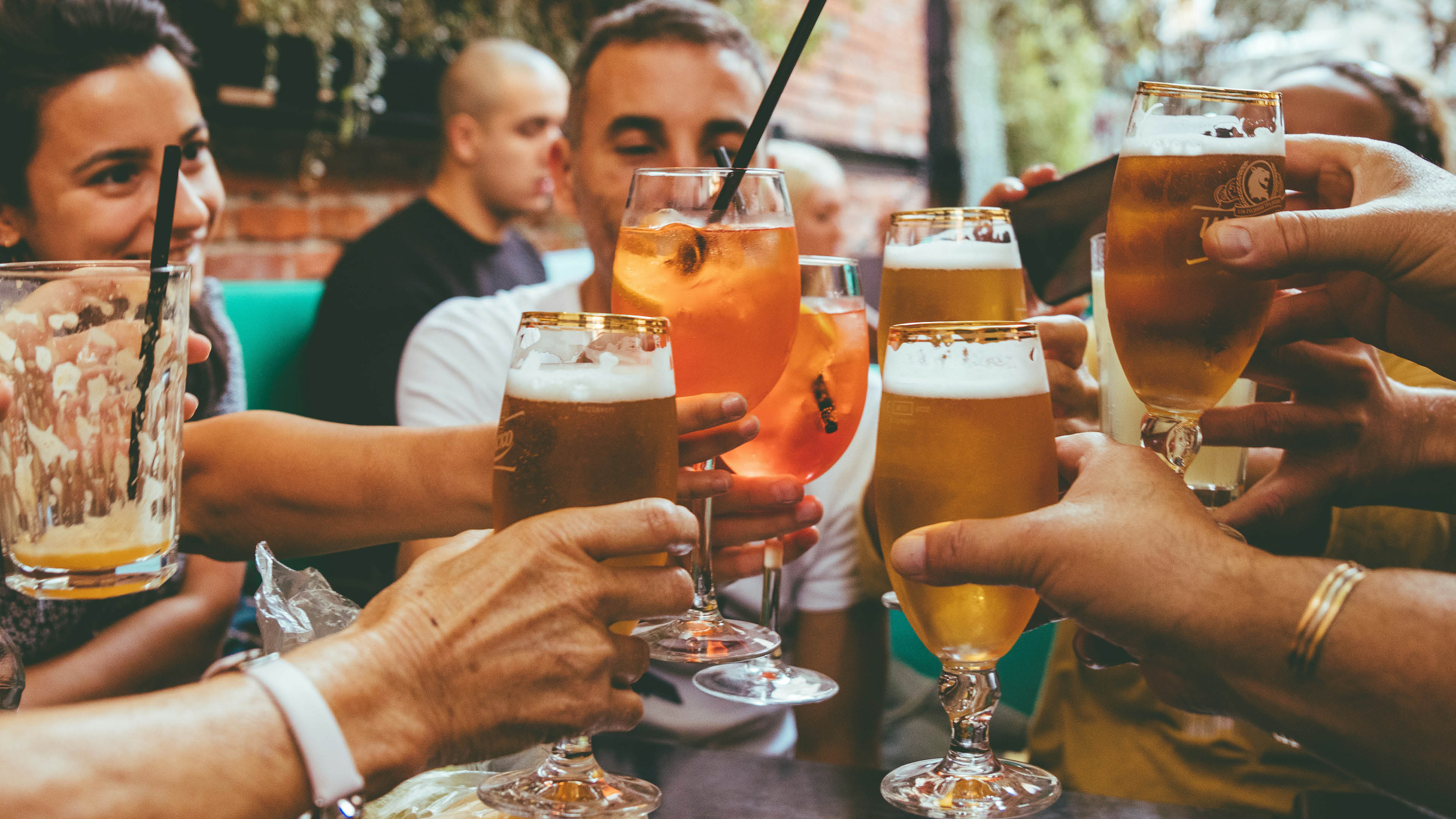 A group of people are sitting around a table with drinks in front of them. Description generated by AI